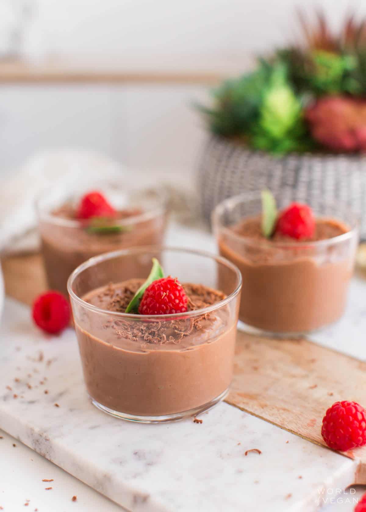 Vegan mousse jars topped with chocolate shavings and raspberries.