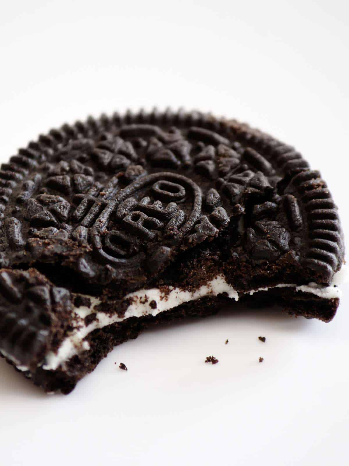 One Oreo cookie on a light background with a bite taken out of the cookie.