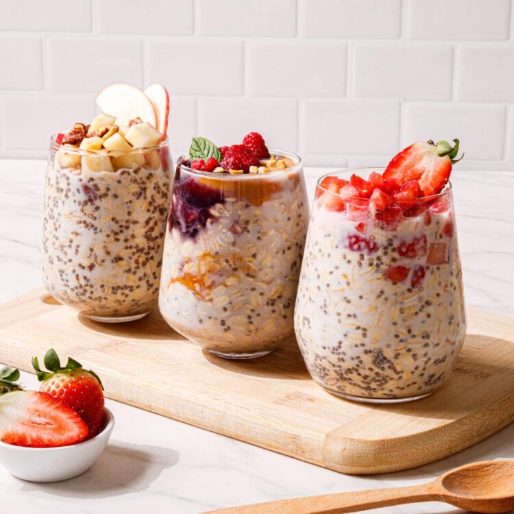 Three jars of vegan overnight oats if different types on a cutting board.