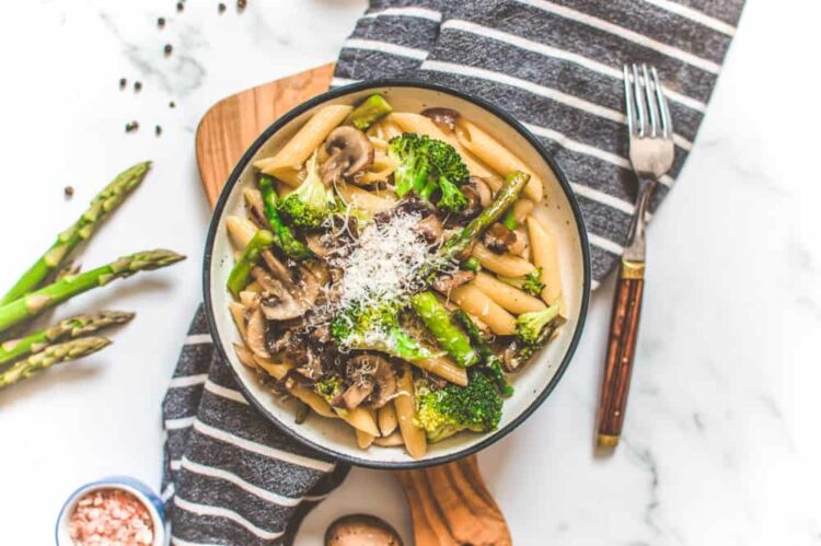 Pasta Dish Served with Vegetables on a Bowl topped with Grated Vegan Cheese