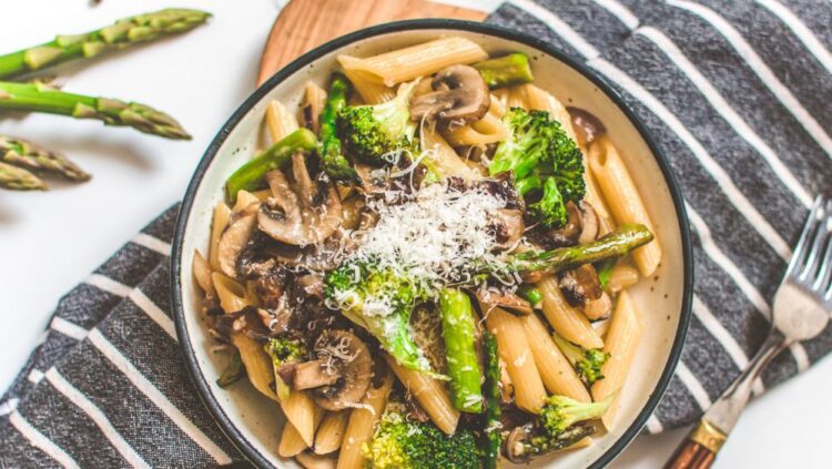 Pasta Dish Served with Vegetables on a Bowl topped with Grated Vegan Cheese