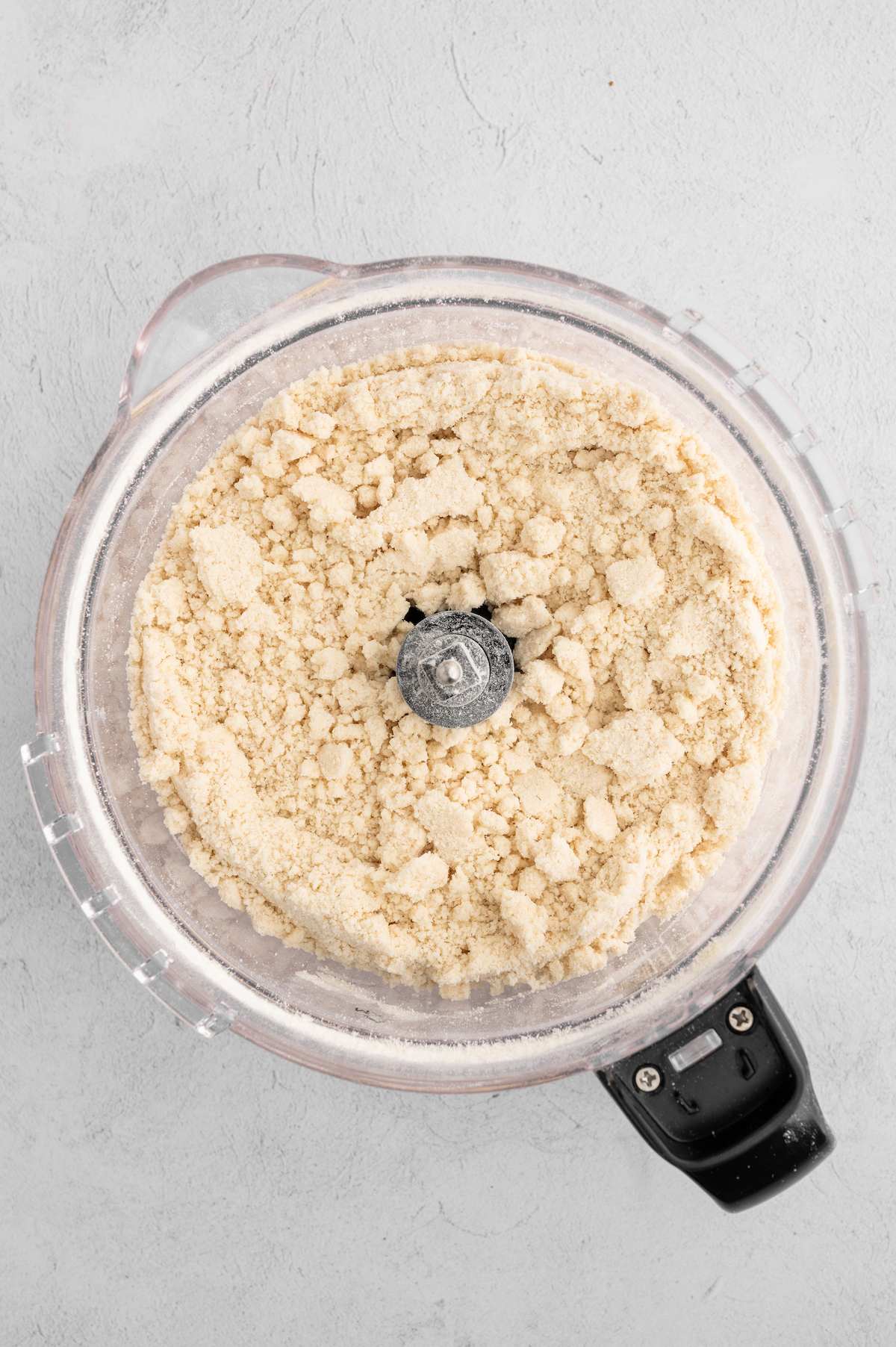 The crumbled vegan pie crust mixture in a food processor before adding water.