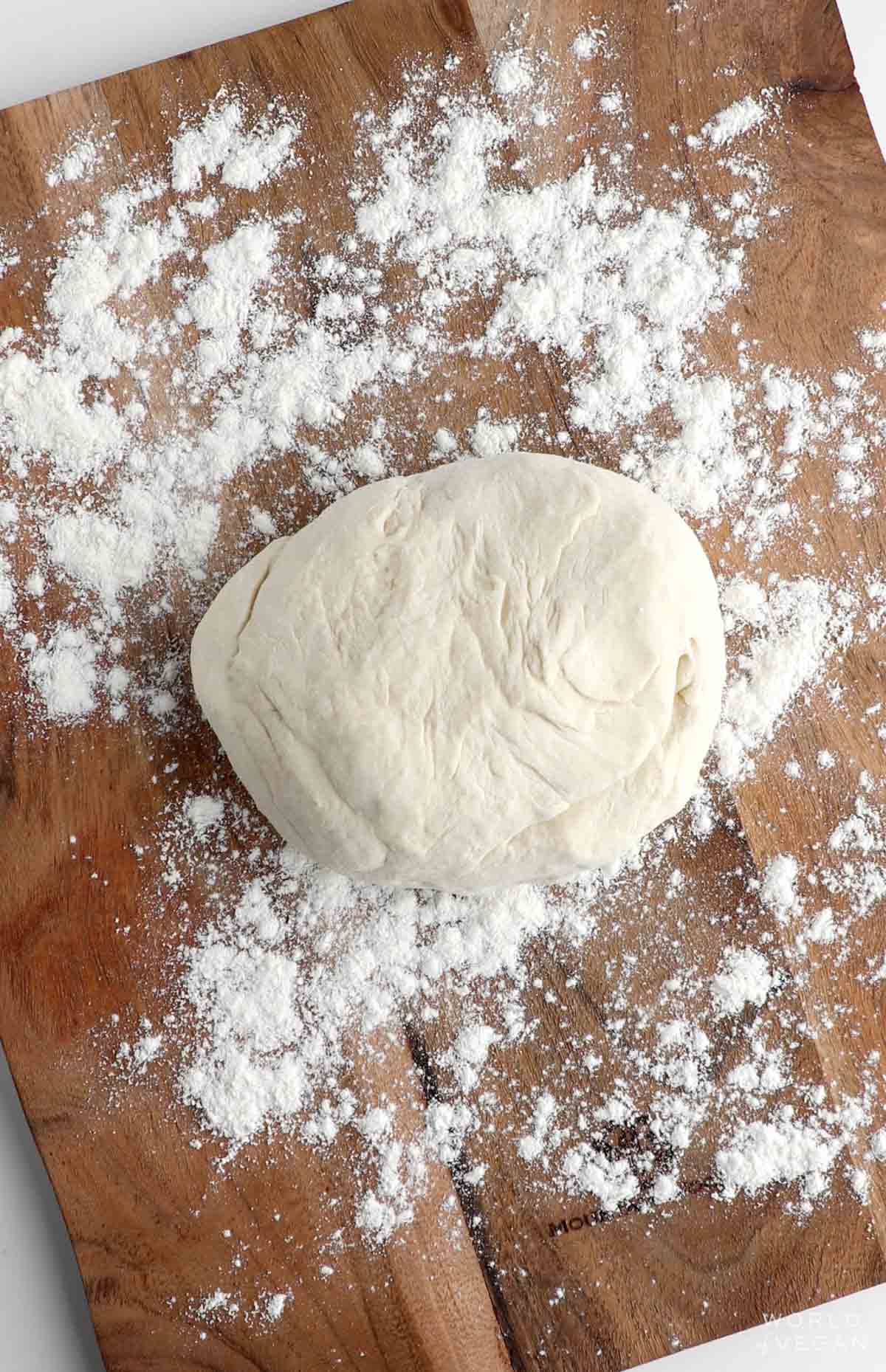 Vegan pizza dough on a floured surface.