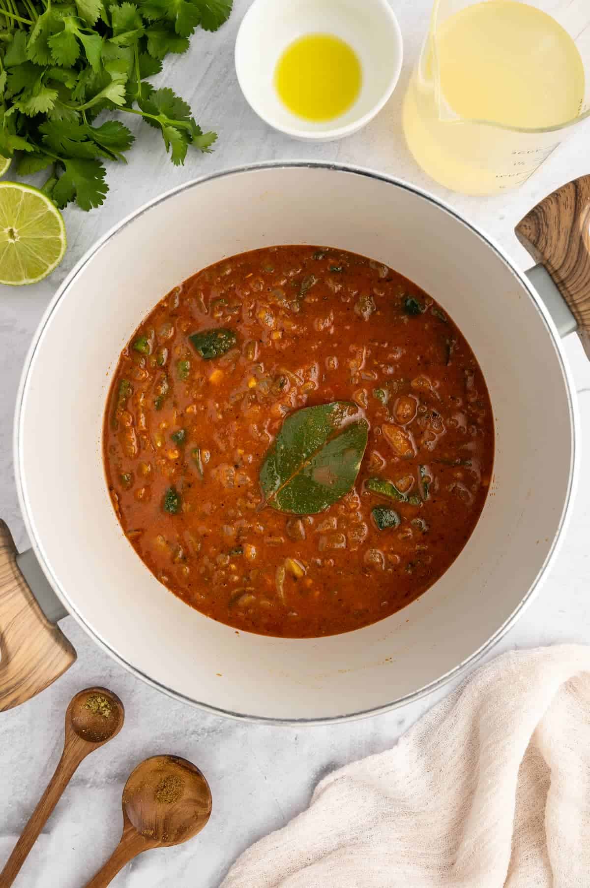 A bowl of vegan pozole being prepped in a white bowl with a bay leaf on top.