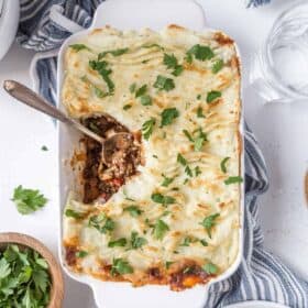 Vegan Shepherd's Pie in a casserole dish with a serving spoon and a serving missing.