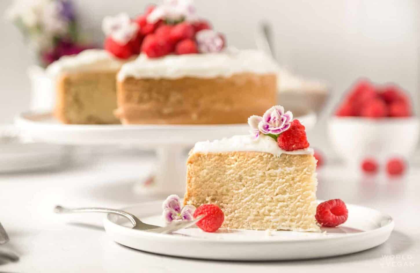 slice of vegan sponge cake decorated with berries and flowers served on a plate