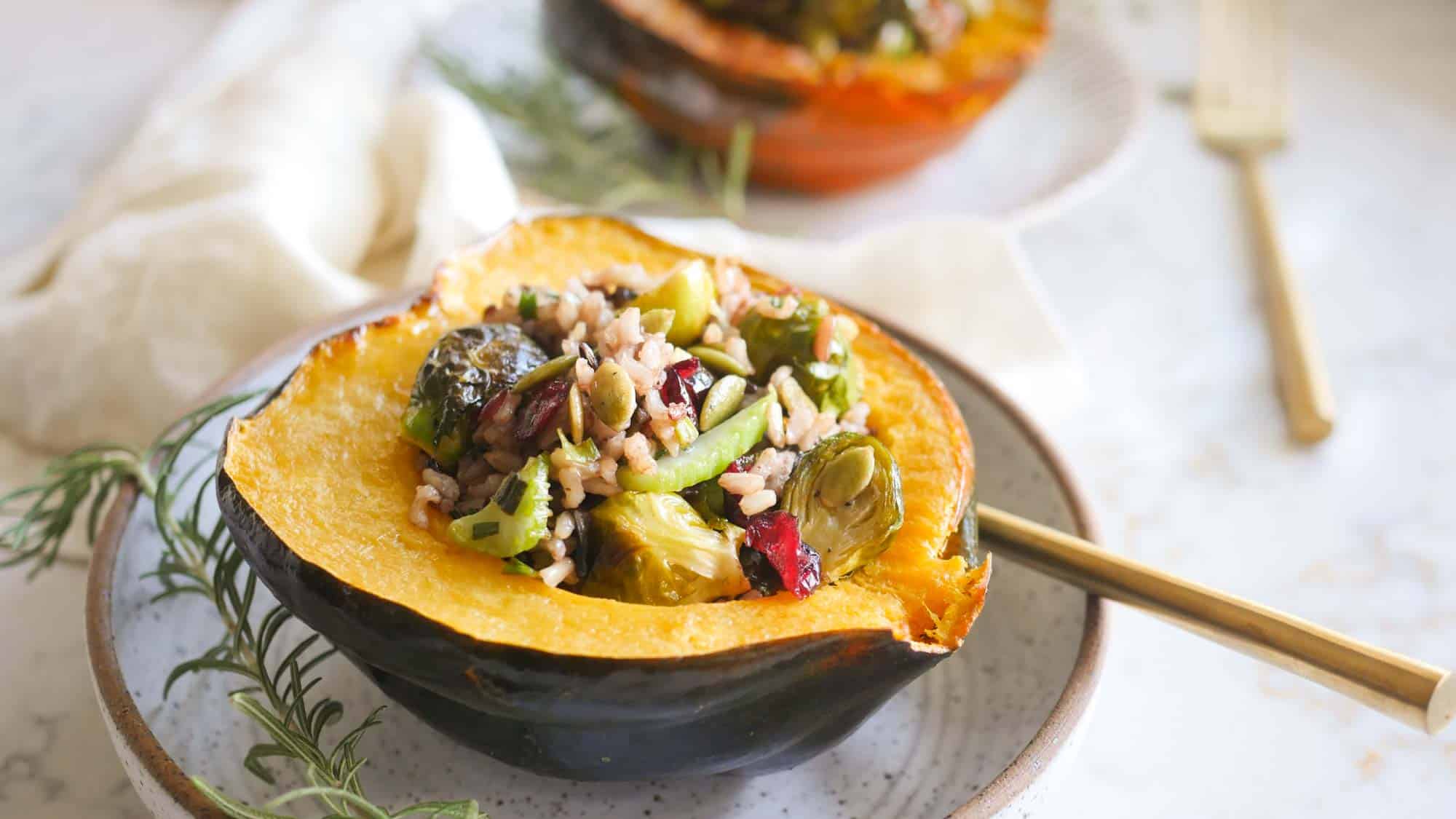 Stuffed Acorn Squash Vegan Thanksgiving Recipe On a Plate With Tahini Dressing and A Sprig of Rosemary