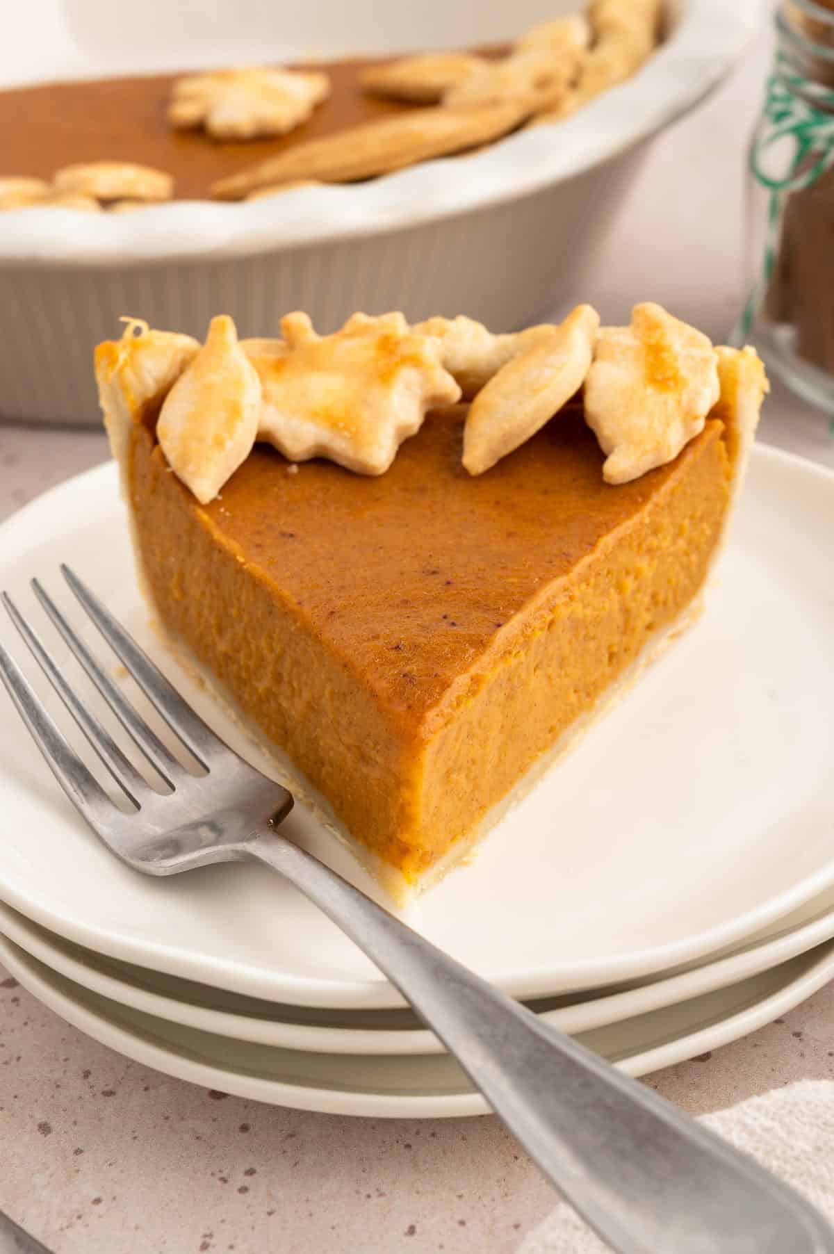 Vegan sweet potato pie on a plate with a fork and decorated with pastry leaves.