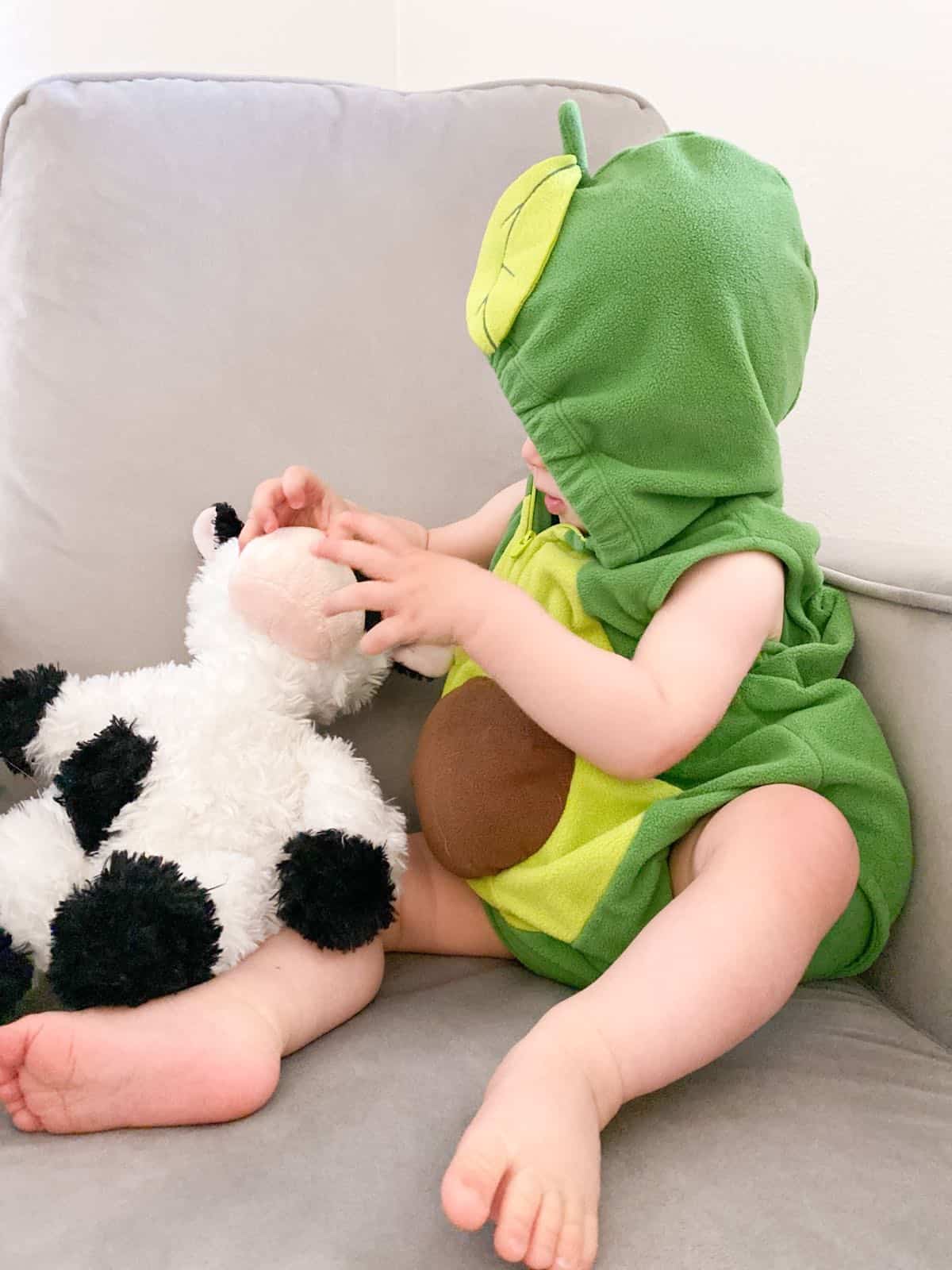Vegan Toddler wearing an avocado Halloween costume and holding a cow