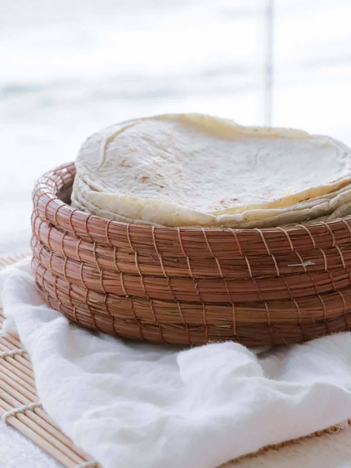 Vegan flour tortillas stacked in a woven basket.