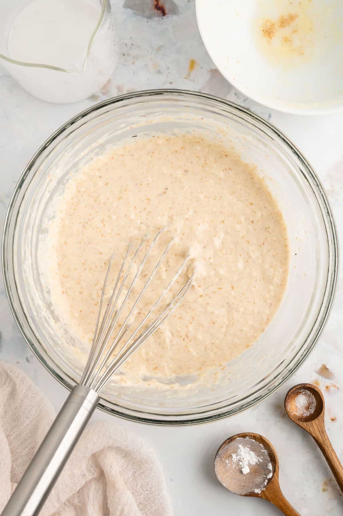 A top-down shot of vegan waffle batter in a bowl with a whisk.