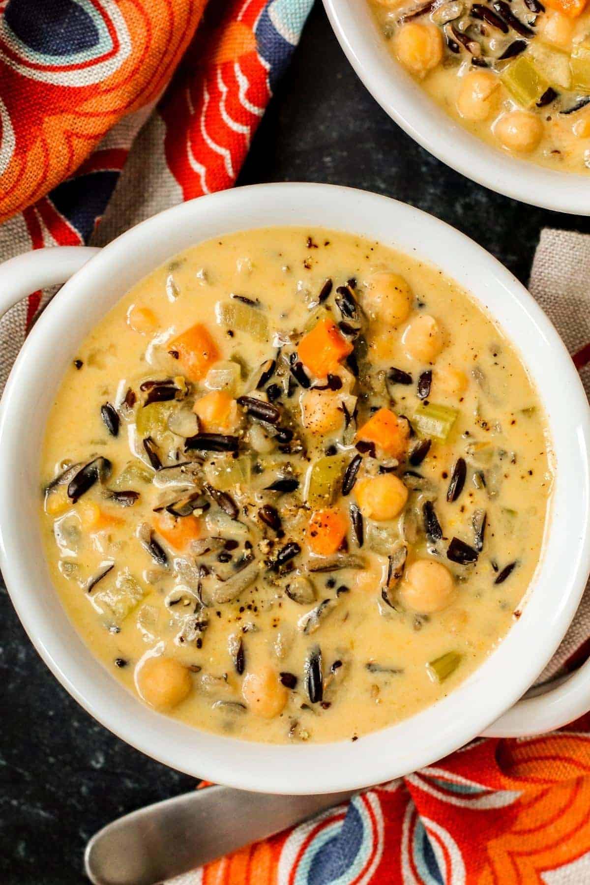 A bowl of wild rice soup next to colorful cloth napkins.