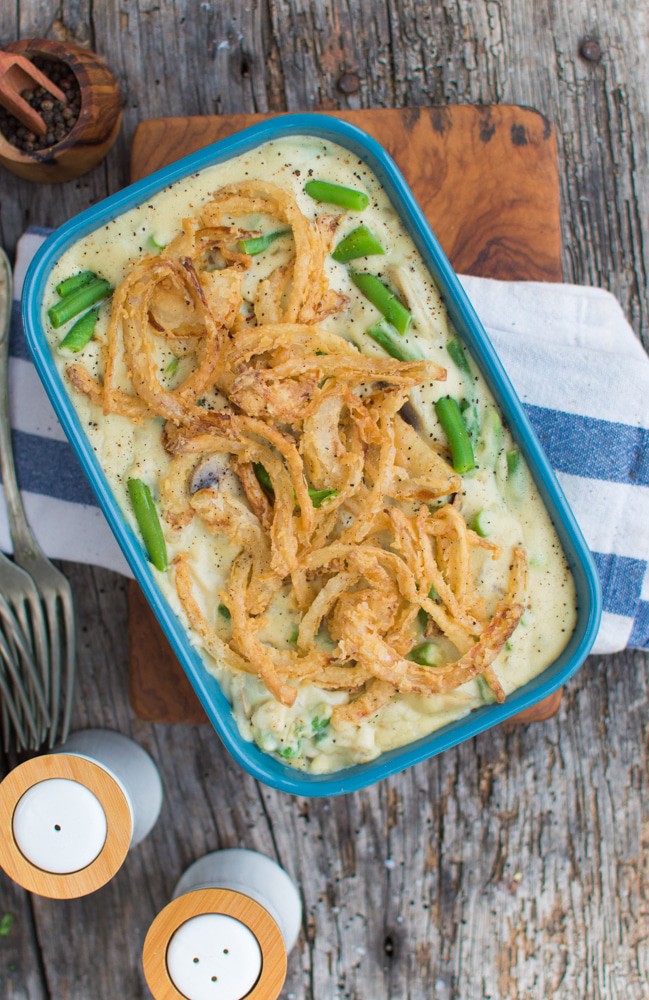 Vegan Green Bean Casserole in a baking dish with a stack of folks and salt and pepper shakers next to it.