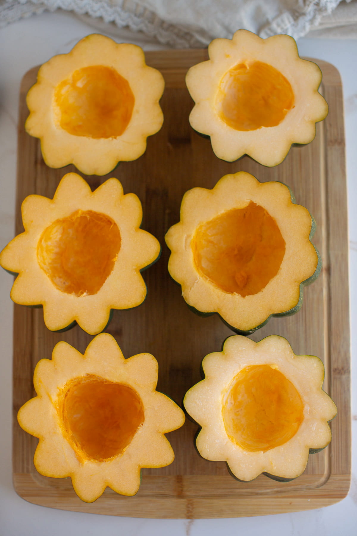 Halved and deseeded acorn squash on a baking sheet.