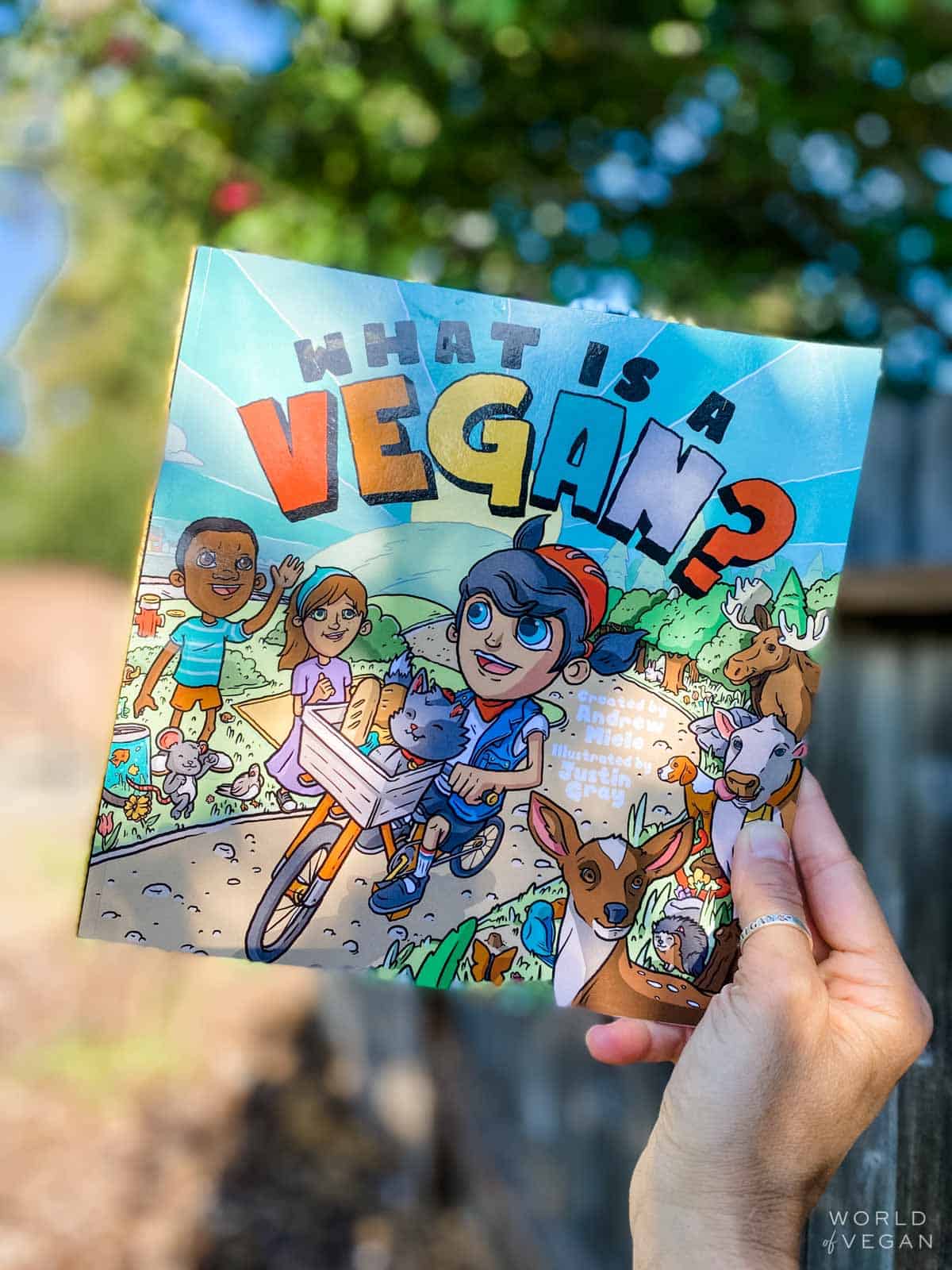 Holding the "What is a vegan?" children's book outside in the garden. 