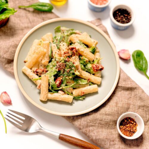 hummus pasta plated with broccoli, spinach, and sundried tomatoes